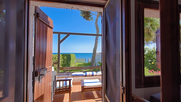 An open door leading to a terrace with a view of the sea, a wooden bench, and a table. - Seafront house with private access to the sea. Completely renovated in 2016 (Pula)