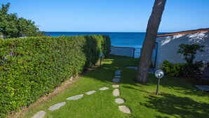 A garden pathway leading to a white building with a view of the sea. - Seafront house with private access to the sea. Completely renovated in 2016 (Pula)