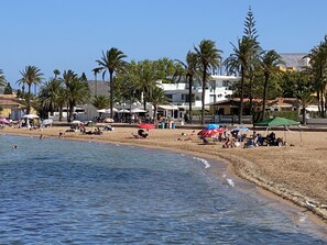 A beach with palm trees, beach umbrellas, and people relaxing. - Penthouse Apart, Roof Terrace, Sea Views, WiFi, Sky, Smart TV, Pool, A/C, BBQ, (Mar De Cristal)