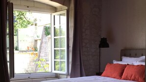 Ein Schlafzimmer mit einem großen Bett, einem Fenster mit Vorhängen, einem Kopfteil und einer Stehlampe.