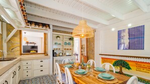 A dining area with a wooden table, white chairs, and a patterned floor. - Cubo's Casa Lucia Private Pool / Wifi / Air conditioning / private garden / BBQ (Alhaurín el Grande)