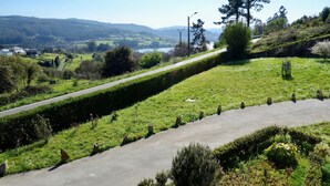 A rural road with a grassy embankment, a clear sky, and distant hills.