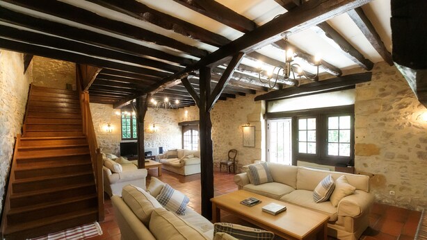 A rustic interior with a wooden staircase, stone walls, and a cozy seating area with sofas and a coffee table. - Wonderful 4 bedroom, 4 bath Perigordine House, heated pool, 5 acres, Sarlat 6km (Saint-André-D'allas)