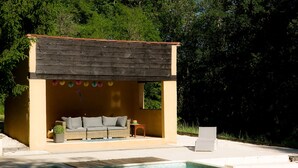 A poolside area with a small wooden structure, a sofa, and a chair. - Wonderful 4 bedroom, 4 bath Perigordine House, heated pool, 5 acres, Sarlat 6km (Saint-André-D'allas)