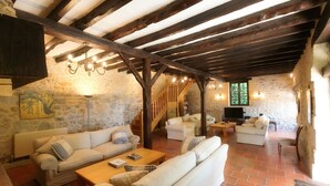 A rustic interior with stone walls, wooden beams, and a stone staircase leading to an upper level. - Wonderful 4 bedroom, 4 bath Perigordine House, heated pool, 5 acres, Sarlat 6km (Saint-André-D'allas)
