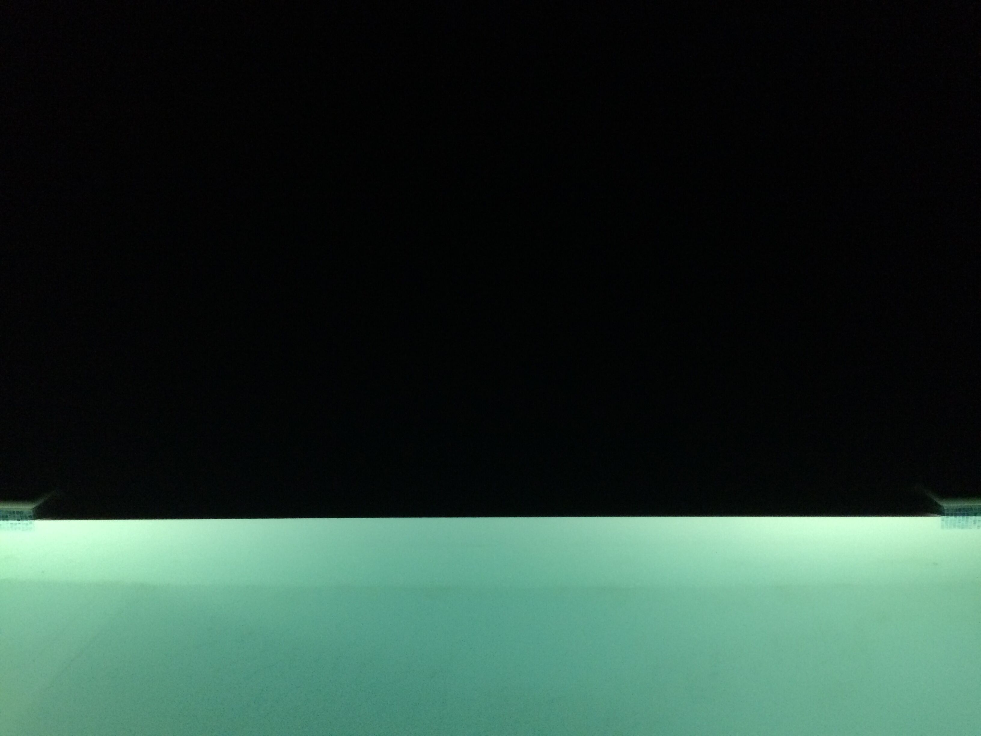 Un intérieur sombre avec un plancher de couleur turquoise et un plafond blanc.