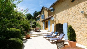 A stone building with a tiled patio, outdoor seating, and potted plants. - Wonderful 4 bedroom, 4 bath Perigordine House, heated pool, 5 acres, Sarlat 6km (Saint-André-D'allas)