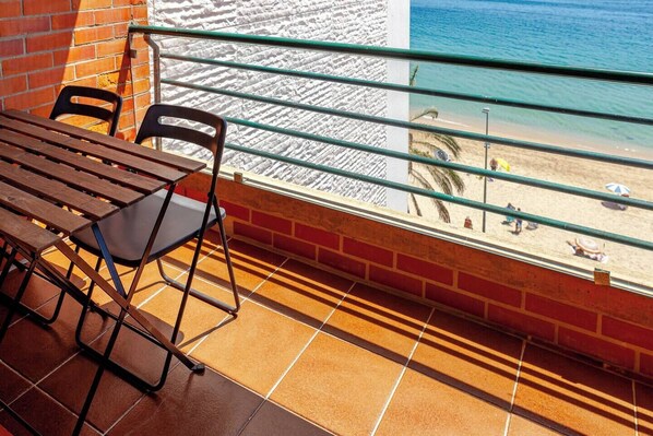 Un balcon avec vue sur la plage, une table et deux chaises.
