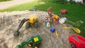 Een kind speelt met zandspullen in een tuin.
