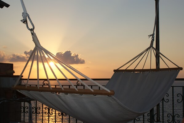 A hammock tied to a metal railing, overlooking a sunset over the water. - B&B Casa Armonia (Pizzo)