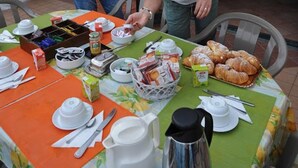 A breakfast setup with a table covered in a floral tablecloth, featuring a variety of breakfast items including croissants, a coffee pot, and a basket of pastries. - B&B Casa Armonia (Pizzo)