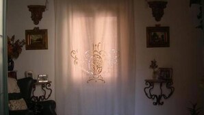 A room with a white curtain, a framed picture on the wall, and a small table with a vase. - B&B Casa Armonia (Pizzo)