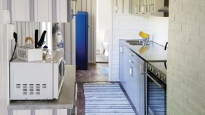 Una cocina con armarios blancos, un refrigerador azul y una toalla amarilla colgada en el lavamanos.