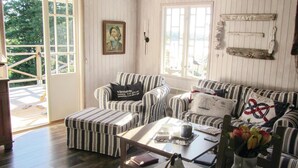 Una sala de estar acogedora con mobiliario tapizado a rayas, una mesita de centro y vistas al exterior.