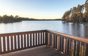 A wooden deck overlooking a calm lake with trees in the background.