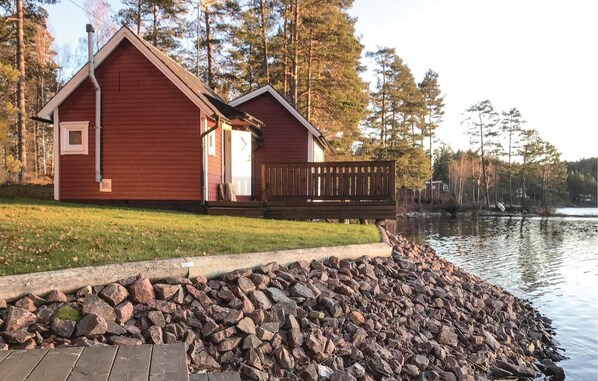 A cabin with a wooden deck and a stone wall by a lake. - Cozy home in Vena with house sea view (Vena)