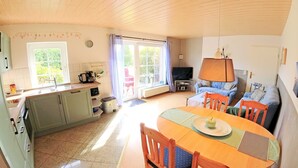 A cozy living room with a wooden dining table, chairs, a sofa, and a TV.