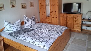 Une chambre à coucher avec un lit en bois, une télévision, une armoire et des tableaux encadrés accrochés au mur.
