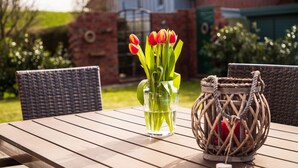 A wooden table with a vase of red tulips and a wicker basket. - North Sea coast, charming Frisian house on the old dike with sauna, fireplace for 2-8 p. (Wangerland)