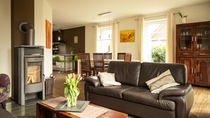 A modern living room with a fireplace, leather sofa, dining area, and kitchen. - North Sea coast, charming Frisian house on the old dike with sauna, fireplace for 2-8 p. (Wangerland)