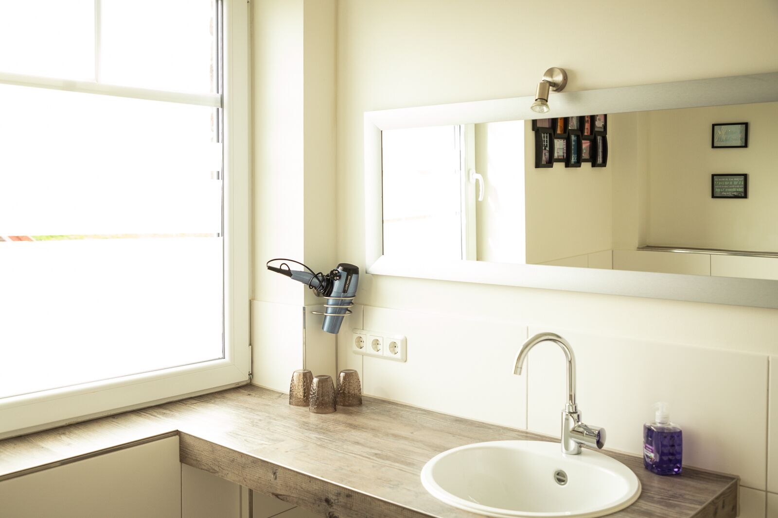 A bathroom with a white sink, a mirror, and a window.