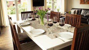 A dining table set for six with wine glasses and plates, surrounded by wooden chairs. - North Sea coast, charming Frisian house on the old dike with sauna, fireplace for 2-8 p. (Wangerland)
