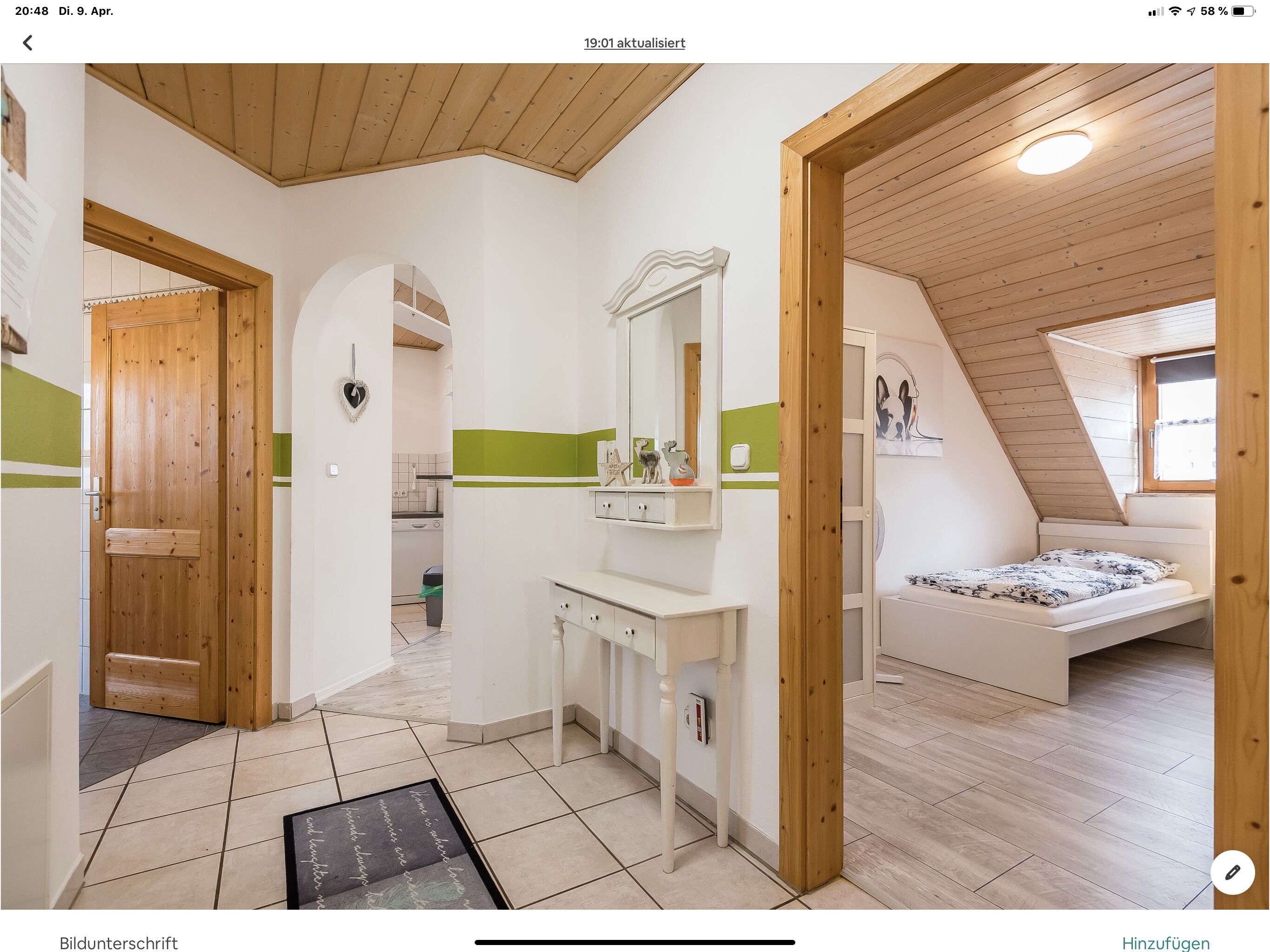 Ein modernes, helles Schlafzimmer im Dachgeschoss mit schrägen Wänden, einem kleinen Fenster und einer Holztür.