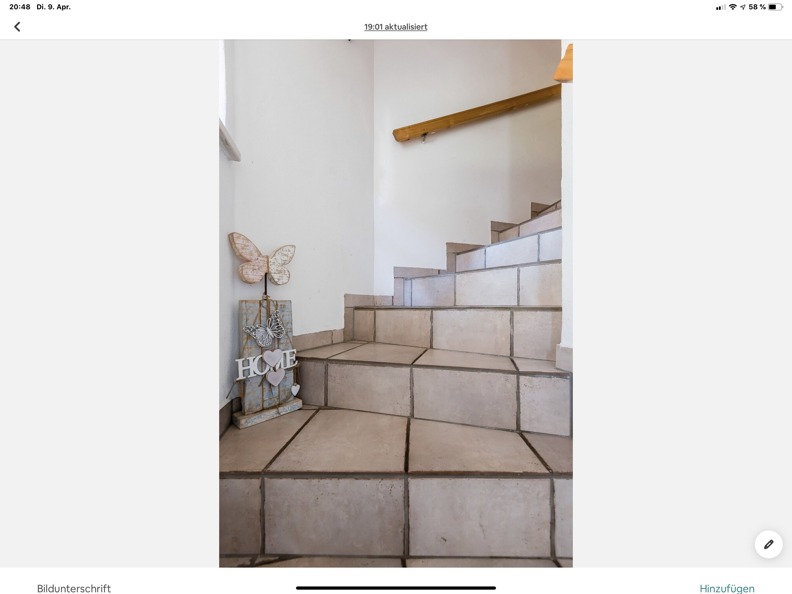 Eine Treppe mit beigen Fliesen und einem Holzgeländer.