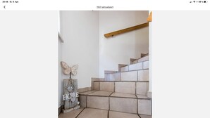 Un escalier avec des carreaux de couleur beige et une main courante en bois.