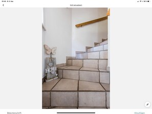 A staircase with beige tiles and a wooden handrail.