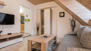Un salon moderne avec un plafond en bois, un téléviseur à écran plat, un canapé et une table basse.