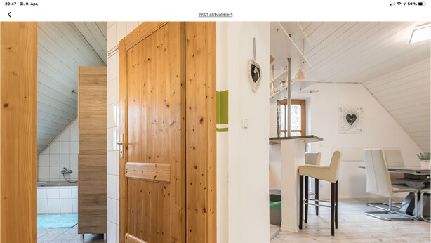 Un intérieur moderne avec une porte en bois, un coin repas comprenant une table et des chaises, et une cuisine équipée d’une cuisinière.