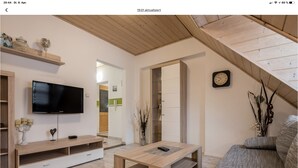 Un salon moderne avec un plafond en bois, un téléviseur à écran plat, un canapé et une table basse.