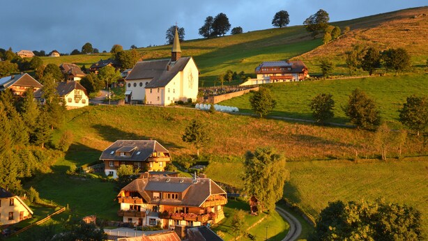 Un village rural avec des maisons traditionnelles, une église et une route sinueuse.