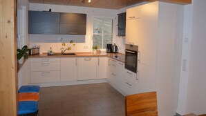 Une cuisine moderne avec des armoires blanches, un plan de travail en bois et un four encastré.