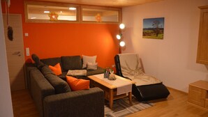 Un salon avec un canapé, un fauteuil et une petite table sur laquelle se trouve une lampe.