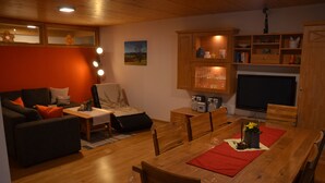 Un salon chaleureux avec une table à manger en bois, un canapé et un téléviseur.