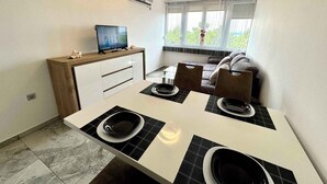 Una cocina compacta con una mesa, sillas y un televisor sobre un mueble de madera.