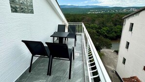 Un balcón con mesa y sillas, con vista a un paisaje montañoso.
