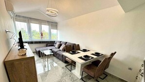 Una cocina moderna con comedor, que presenta piso de mármol, horno empotrado y ventana con persianas.