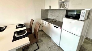 Una cocina compacta con armarios blancos, un microondas integrado y un lavabo.