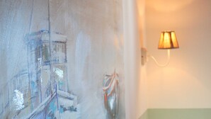 Un mur orné d’un tableau à motifs et une lampe fixée au mur.