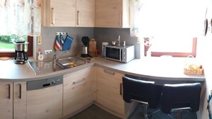 Una cocina con horno empotrado, cafetera, microondas y fregadero.