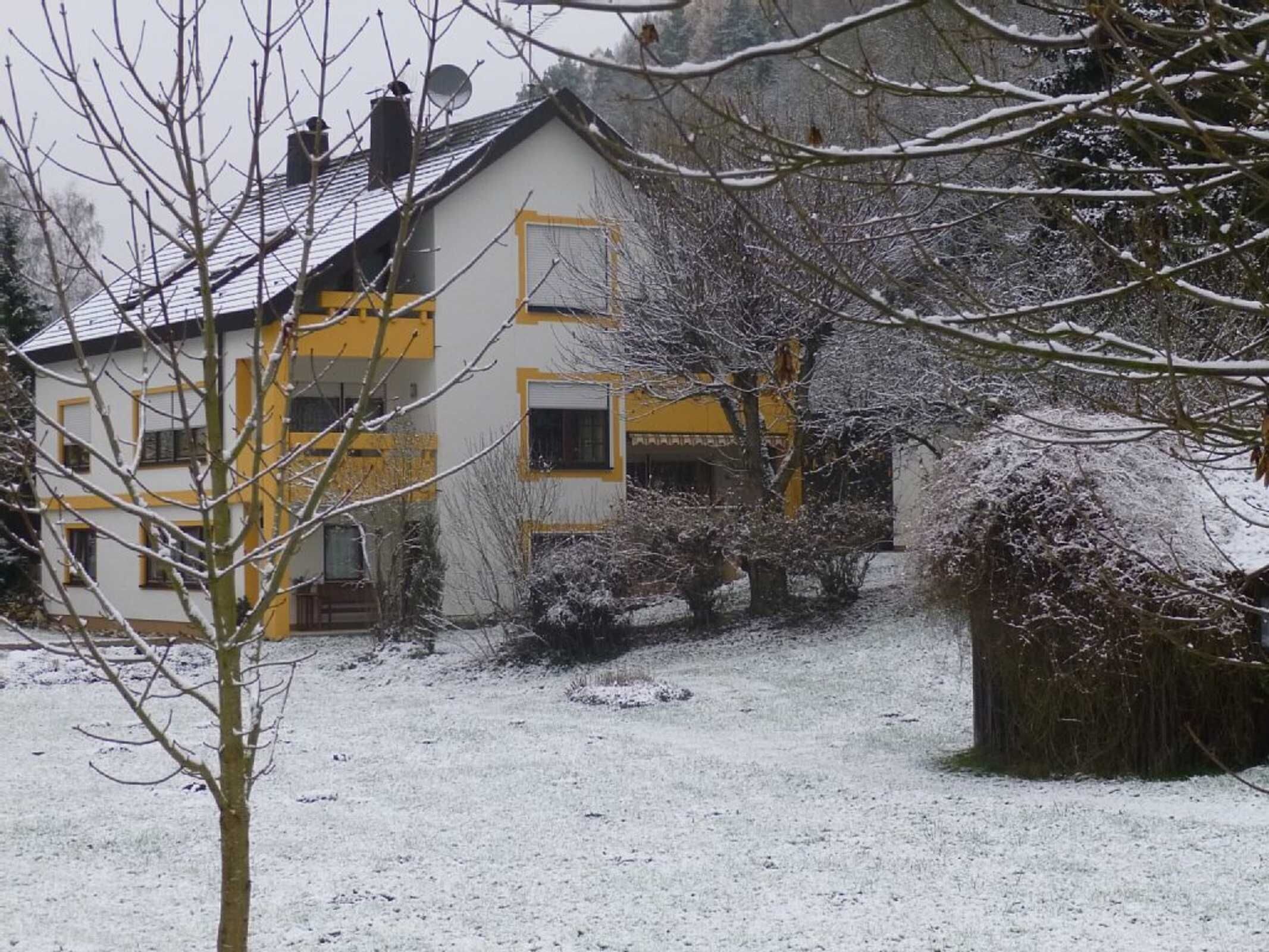 A two-story building with a snow-covered roof and a visible satellite dish.