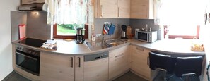 A kitchen with a built-in oven, a coffee maker, a microwave, and a sink.