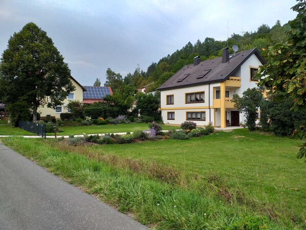 A two-story house with a sloped roof, solar panels, and a well-maintained garden.