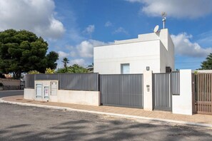 Um edifício moderno com portão fechado, antena parabólica e pequeno depósito.