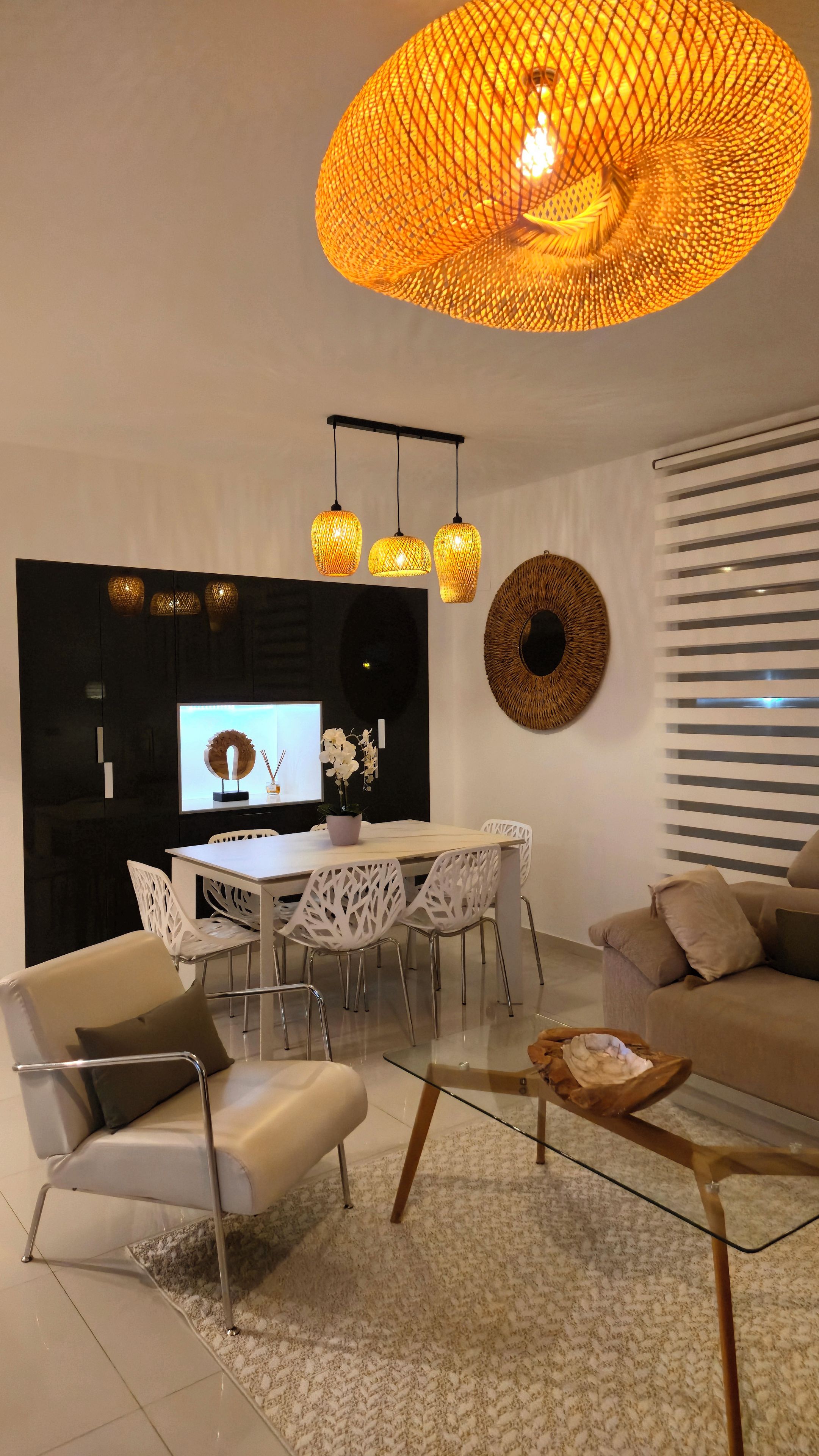 Un salon moderne avec une table basse en verre, des chaises blanches, un canapé et un téléviseur.