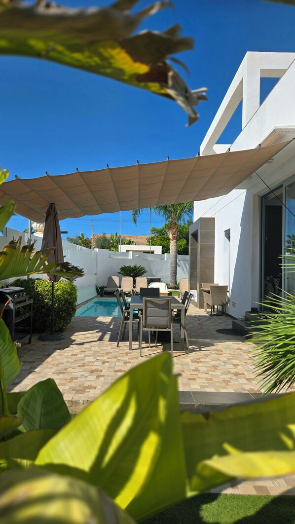 Eine moderne Außenpatio mit Pool, Sitzbereich und überdachtem Bereich.