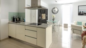 Una cocina moderna con una isla central, estufa integrada y un reloj grande en la pared.